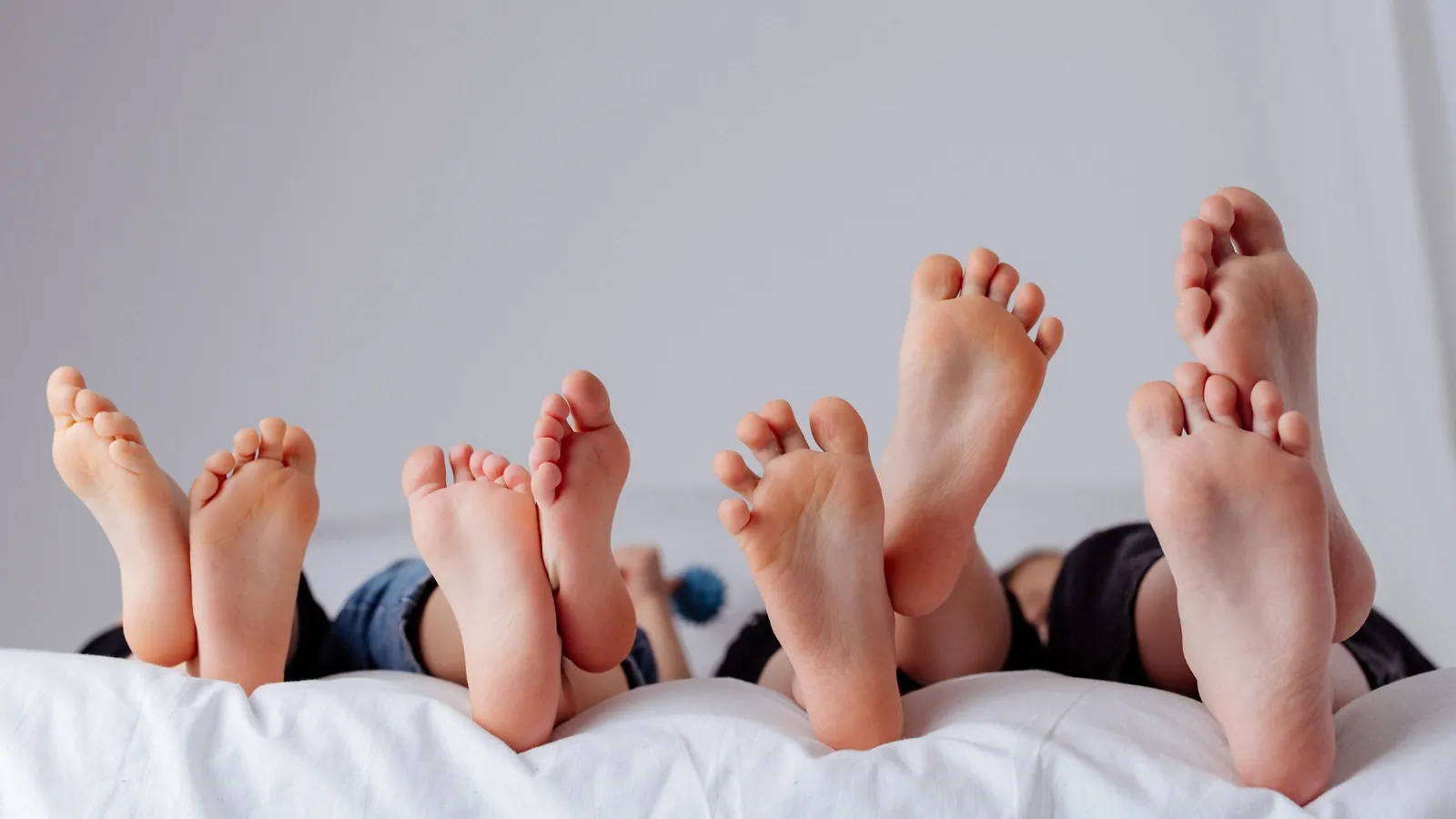 Füße von Kindern und Erwachsenen auf dem Bett